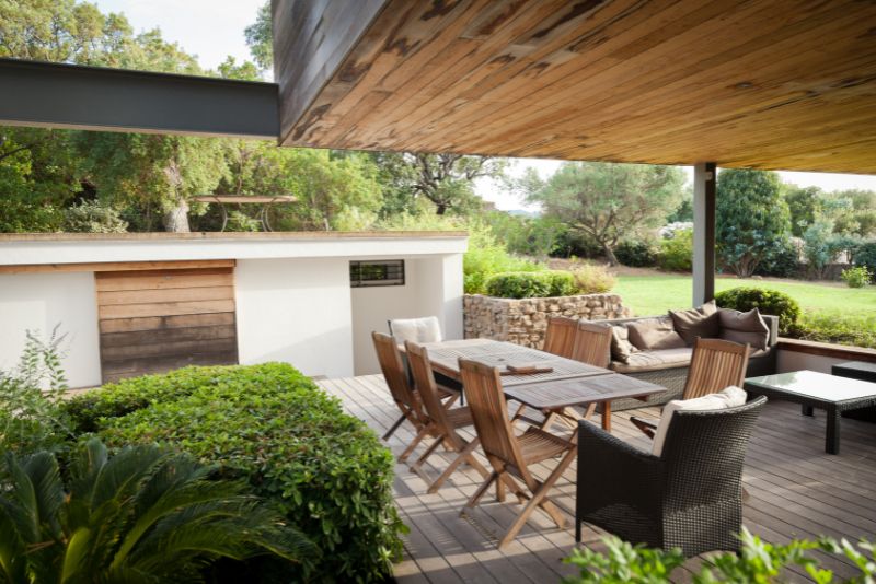 pergola with dinning table and chairs and decorative plants growing around it